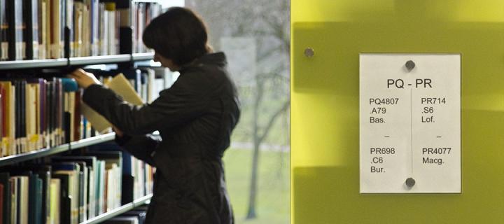 Woman putting book on library shelf