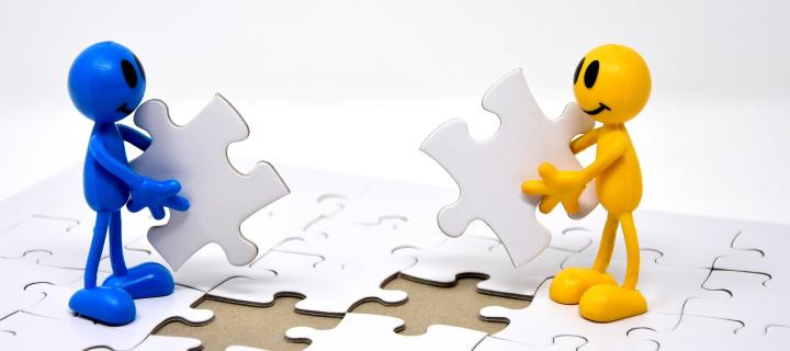 two miniature cartoon figures completing a puzzle together