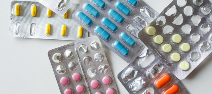 A pile of packets of pills of different colours and shapes