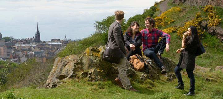 Undergraduate students on Arthur's Seat with panoramic view of the city in the background