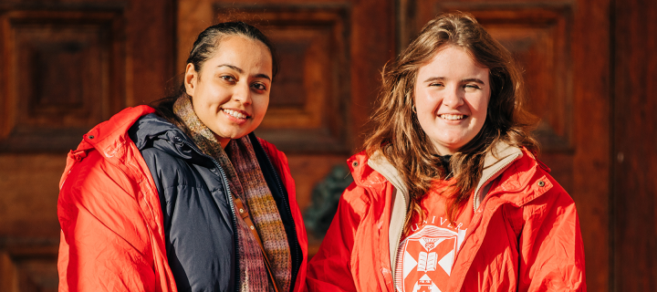 Student ambassadors stand outside McEwan hall, wearing red coats
