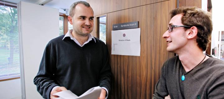 A male lecturer talking with a male student in the Business School