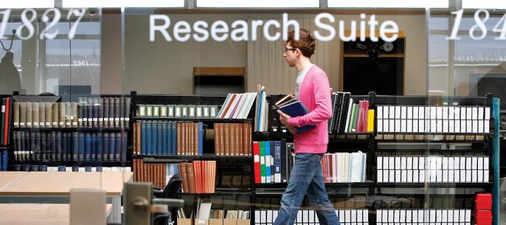 Student walking through research suite in main library