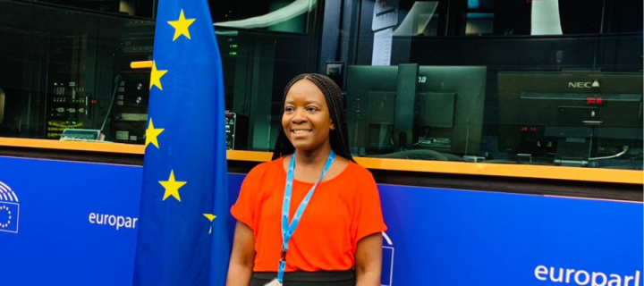 Amanda Wanyonyi is at the European Student Assembly with the flag of European behind her