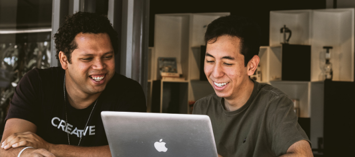 Two men smiling and looking at a laptop