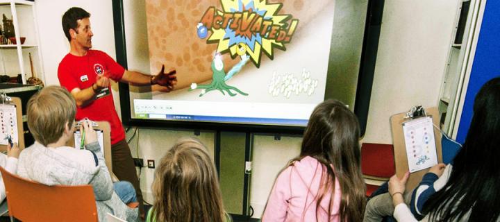Medical researcher discussing an immunology cartoon with children in a Science Festival workshop