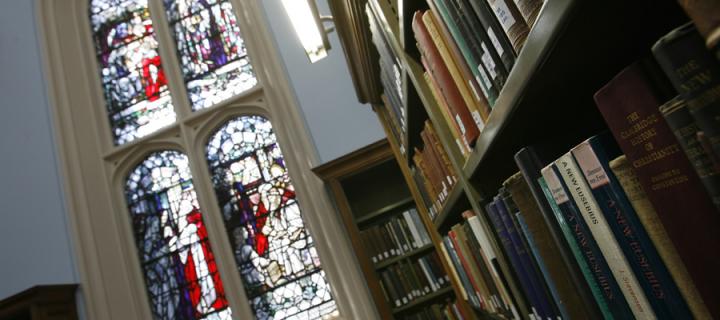Colour photo of some books in front of a stained glass window.