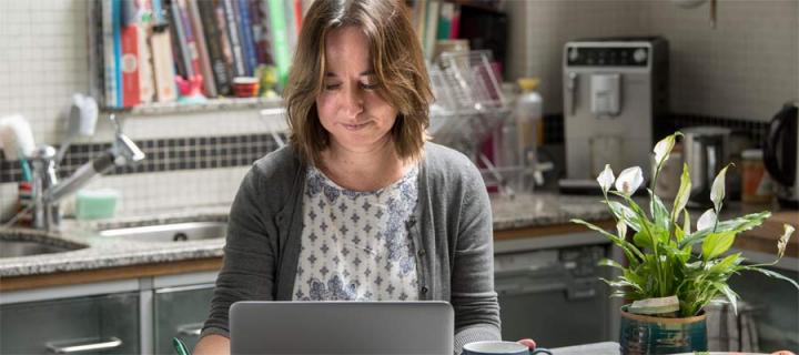 woman works at laptop at kitchen table