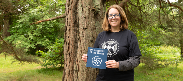 Vanessa McCorquodale in woodland setting,  holding Sustainable Development Goal 17 card, partnership for the goals