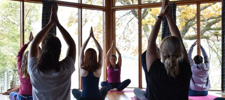 A group practicing yoga in the dinning room at Firbush 
