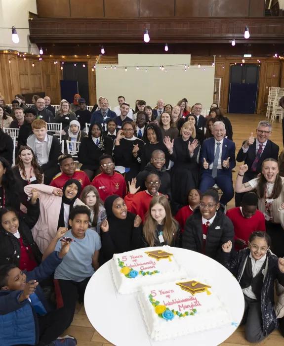 A group of school pupils, University staff and IntoUniversity staff pose for a group photo in a hall, to celebrate IntoUniversity Scotland's 5 year anniversary