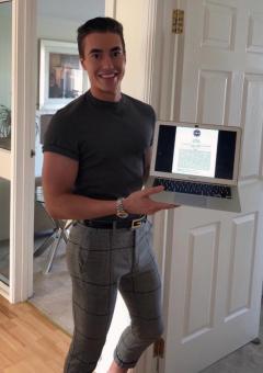 A photograph of Adam McGeoch holding his laptop when completing the MSc Dissertation Submission