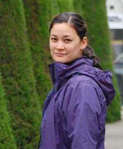 Photo of Andrea Weiss wearing a purple coat, turning towards the camera.