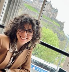 Carolina Buffoli smiling at camera inside a cafe with Edinburgh Castle in the background.