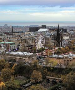 A view across Princes Street Gardens with a ferris wheel and the Scott Monument prominent