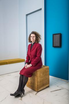 Photograph of Revd Dr Harriet Harris MBE, University Chaplain, sitting on a gold stool in The Sanctuary in Chaplaincy Centre.