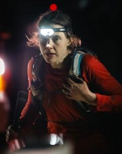woman wearing a head torch running in the dark