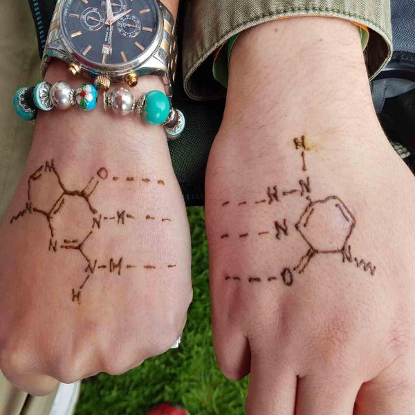 Two hands with henna tattoos of cellular structures