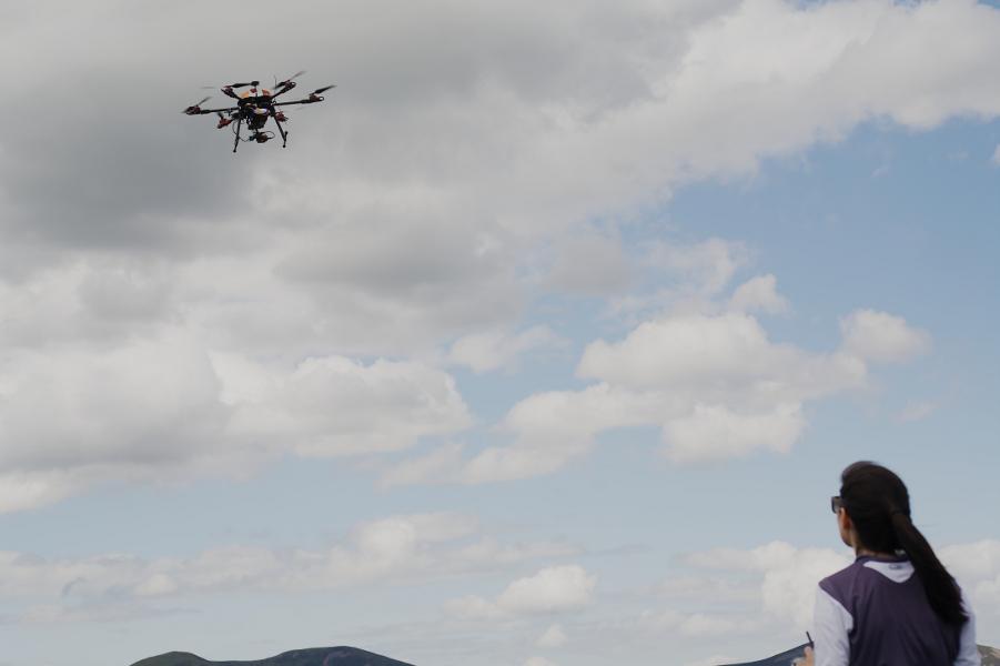 T680 drone in flight with remote pilot looking on