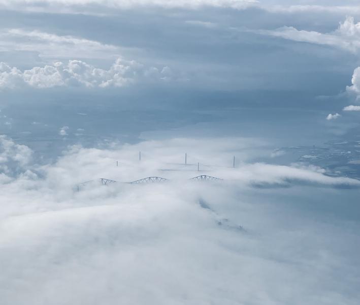 Ariel image showing three bridges poking through cloud cover. 