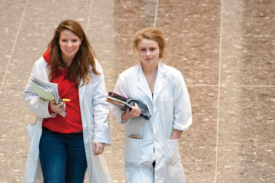 Two happy vet students walking with lab coats on