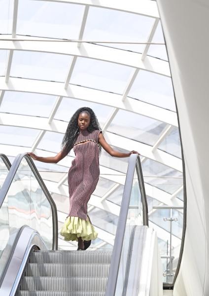 Model poses in a dress at the top of an escalator 