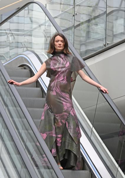 Model poses on an escalator wearing a dress