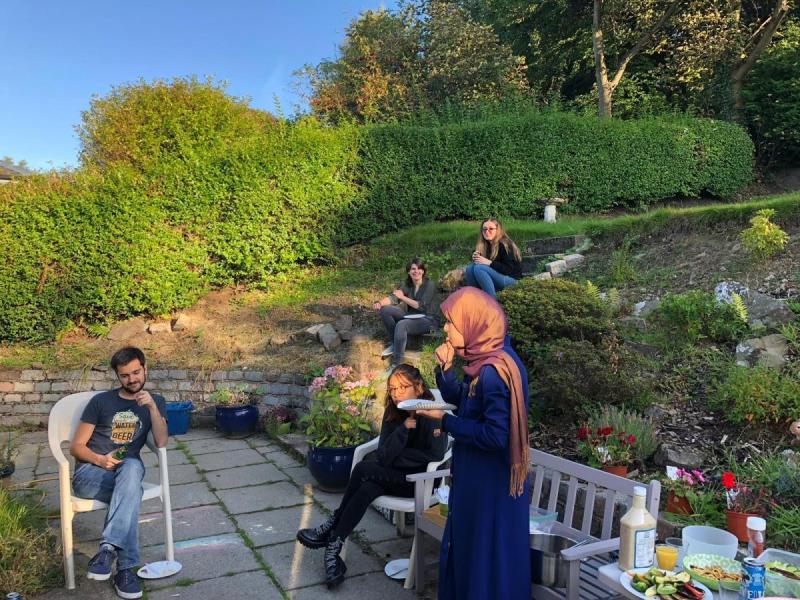 La members sit around a garden with food and drink