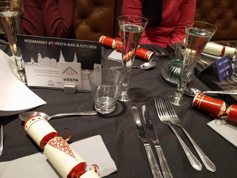 Table in restaurant laid out for Christmas meal, with cutlery, crockery and crackers