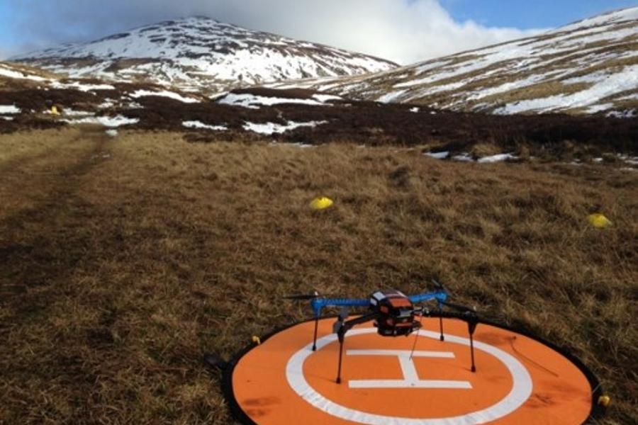 An Iris Plus drone on an orange launchpad with the Scottish mountains in the background