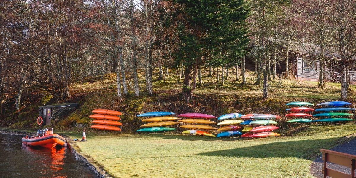 Kayaks lined up along the grass beside the harbour at Firbush 