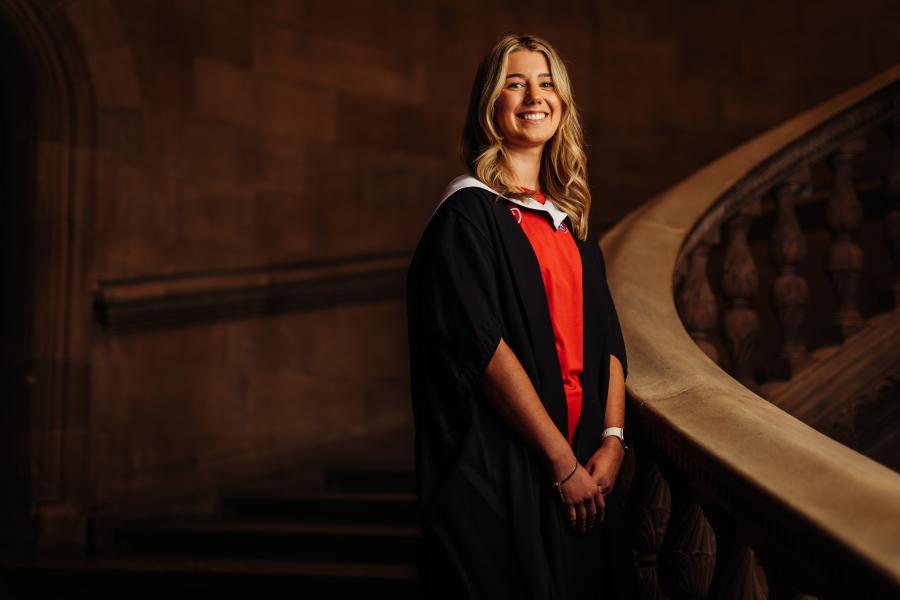 Claire Fillingham wearing graduate gown and sports kit on McEwan Hall staircase