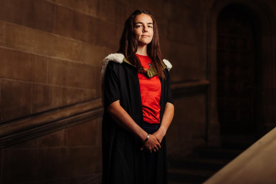 Eve Lawson-Statham wearing graduate gown and sports kit on McEwan Hall staircase