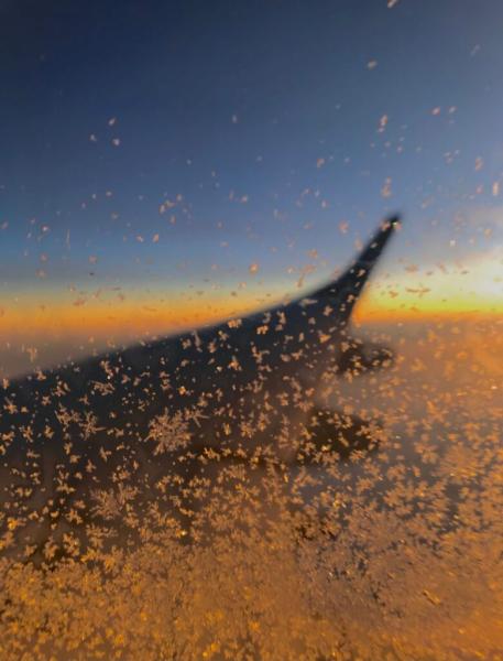 airplane wing out window with ice crystals
