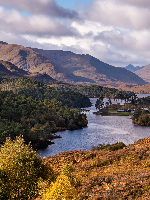 A Scottish loch surrounded by mountains with autumn foliage